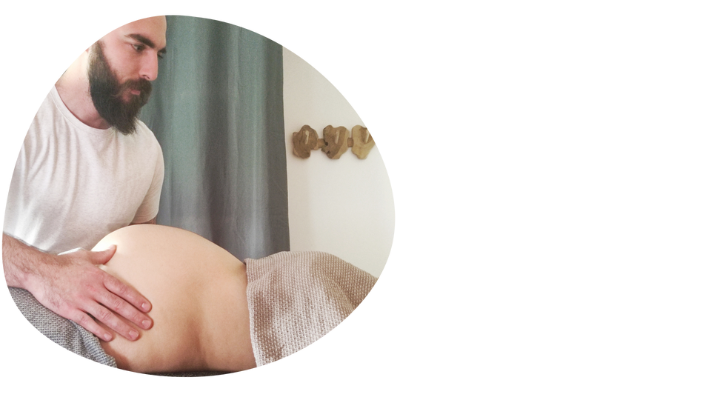 Le praticien masse le ventre de la femme enceinte pendant un massage prénatal.